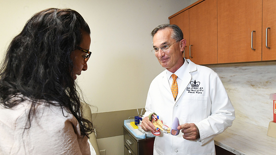 A photograph of Dr. Chabot in an exam room with a patient. He is holding a model of the pancreas.