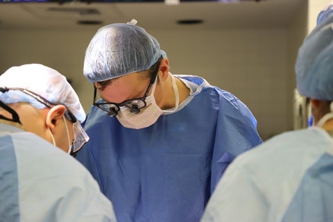Three surgeons in surgical clothing gathered around operating